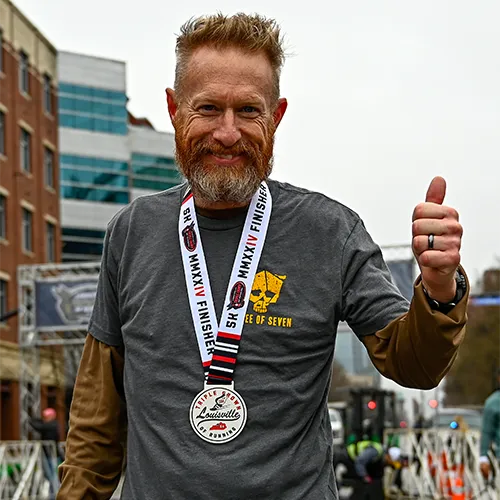 5k man with medal giving thumbs up